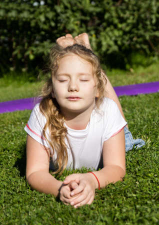 Upset little girl lies on green grass and thinking about.の写真素材