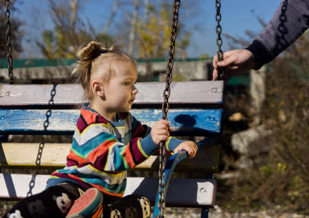 little sad girl on a swing in the park.の写真素材