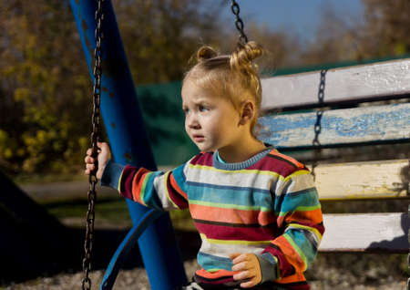 little sad girl on a swing in the park.の写真素材