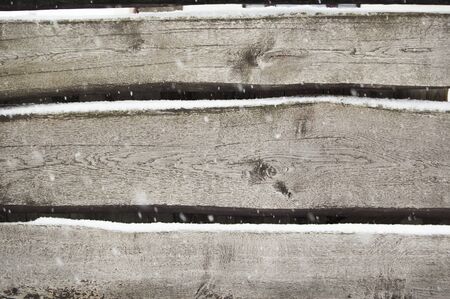 old dark wooden fence in snow. wood background with snowflakes.の写真素材
