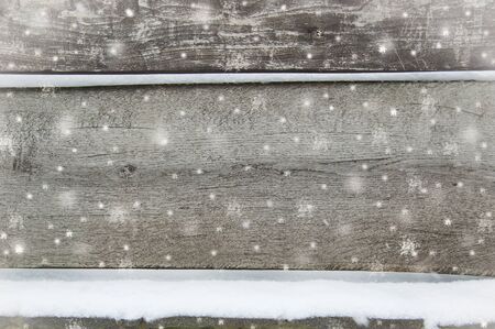 old dark wooden fence in snow. wood background with snowflakes.の写真素材