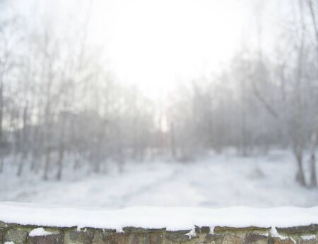 Blurred winter forest background in snow. Old stone fence on the foregroundの写真素材