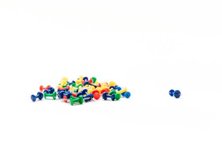 one blue pushpin lies separately from the rest of the heap of the same buttons on a white background