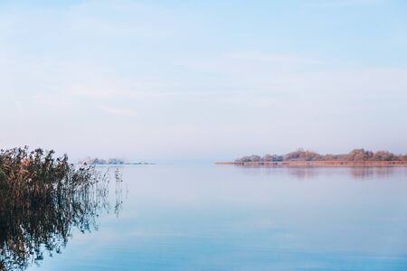 Autumn strip of trees is mirrored in the smooth surface of the lake. Beautiful landscape.の写真素材