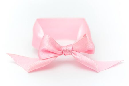 One pink bow bracelet lie on a white background. Symbol of the sexual identity of the girl, close-up.の写真素材