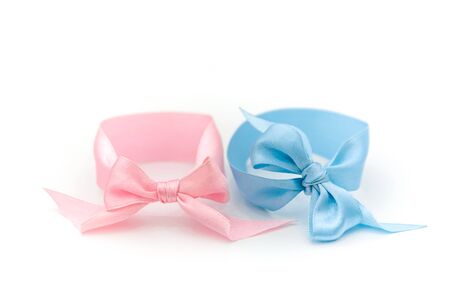 Two pink and blue bow bracelets together lie on a white background. Symbol of the sexual identity of the boy and girl.の写真素材