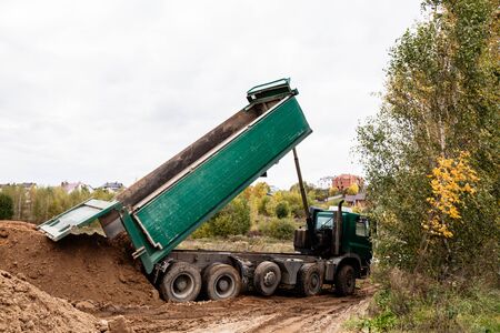 A large green 70-ton dump truck brought sand to a new construction site to add landの写真素材