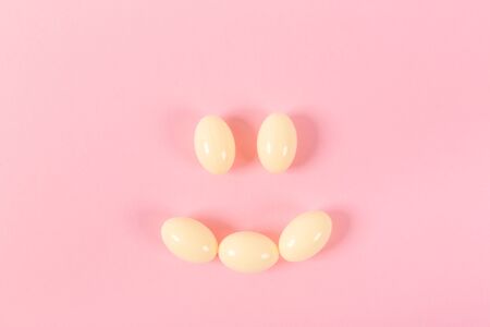 Composition of pills and capsules on a pink background in the form of a smile. Happy emotions. Psychological help. Good day.の写真素材