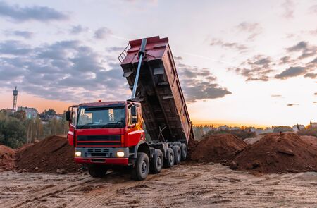 A dump truck is dumping gravel on an excavation site, building landscapeの写真素材