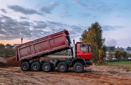 A dump truck is dumping gravel on an excavation site, building landscapeの写真素材