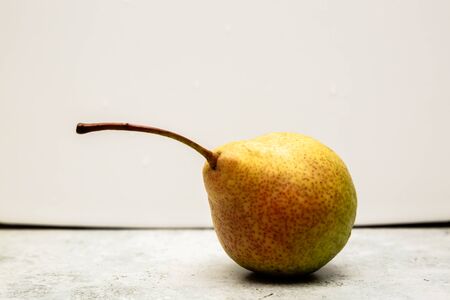still life of one sweet juicy pear lies on a tiled tableの写真素材