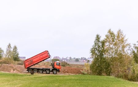 A large red 70-ton dump truck brought sand to a new construction site to add landの写真素材