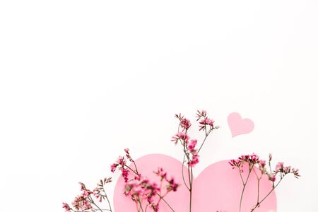 A large pink heart with a place for text decorated with small pink flowers on a white background, symbol of loveの写真素材