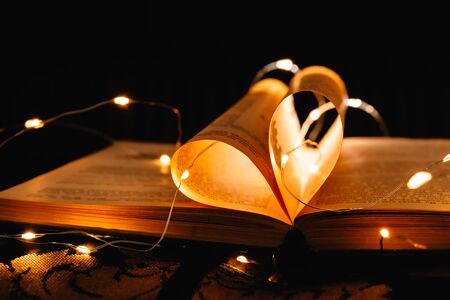 art book novel with sheets in the shape of a heart decorated with bright garland lights and...