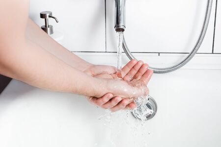 Man washing soapy hands in bathroom. Personal hygiene. Pure clear purified tap water. Close-up.