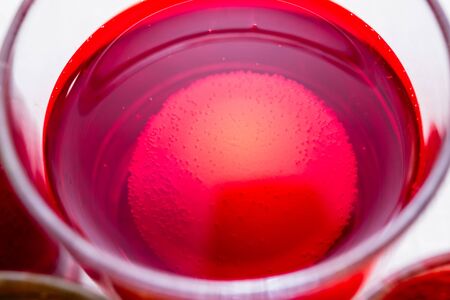 Painting process of Easter egg by dye in the glass. Home decorations for the holiday. Close-up.