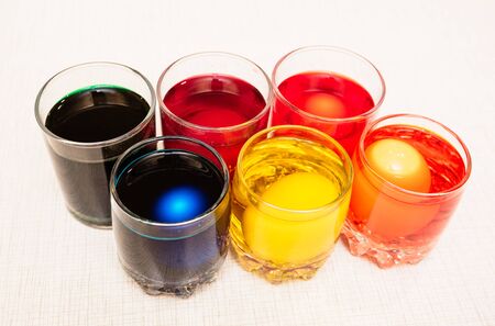 Painting process of Easter eggs by dye in the glasses. Home decorations for the holiday. Close-up.の写真素材