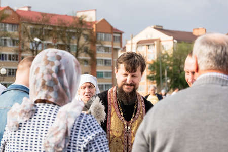 Beryoza, Belarus - April 27, 2019: The priest follows the Christian religious tradition of sprinkling believers and their Easter cakes, painted eggs and candles, with holy water, near the church.のeditorial素材