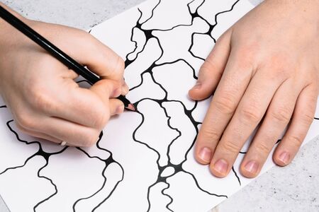 Man is drawing an abstract imaginary picture of curves by a black pencil in his hand. A...