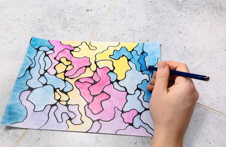 man draws an abstract imaginary picture with a pencil and decorates it with different colors, a...
