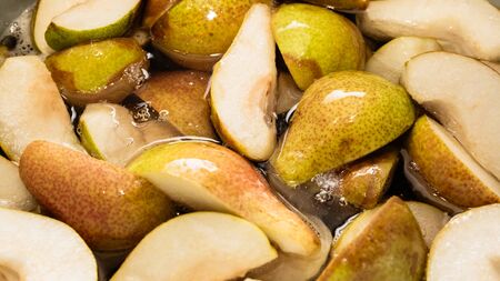 Sliced sweet pears in a quarter are cooked with sugar to prepare the filling for the pie or canning in the form of jam. Slices in own juice close-up.の写真素材