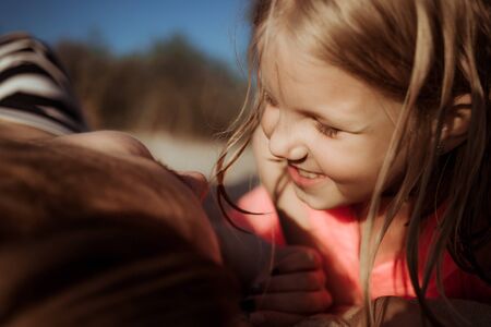 Sunny day, mom and daughter hug and chat together. Summer time vacation or holiday weekend on the beach. Psychology of communication of a single mother with a child. Close-up.の写真素材