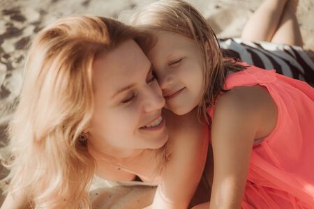 Sunny day, mom and daughter hug and chat together. Summer time vacation or holiday weekend on the...