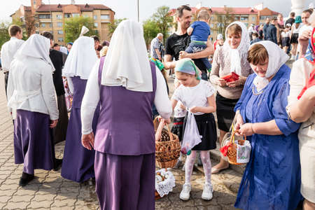 Beryoza, Belarus - April 27, 2019: The priest follows the Christian religious tradition of sprinkling believers and their Easter cakes, painted eggs and candles, with holy water, near the church.のeditorial素材