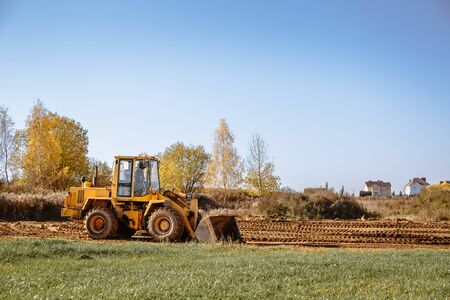 large yellow wheel loader aligns a piece of land for a new building. Preparation of the land for the...