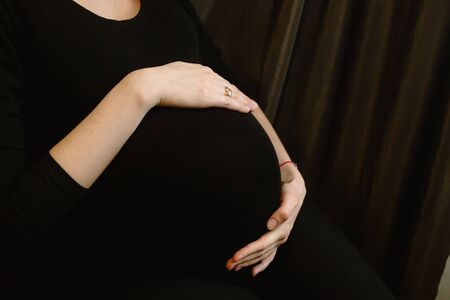 Motherhood, expectation of a beloved child. Mom strokes a large belly at the end of pregnancy. A...