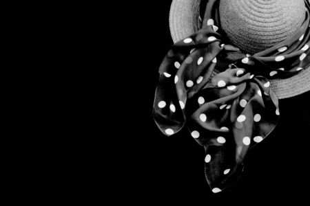 Hat with a scarf on a black background. Symbol of sorrow and sorrow. Fashionable satin and straw accessory for women wardrobe. Top view.の写真素材