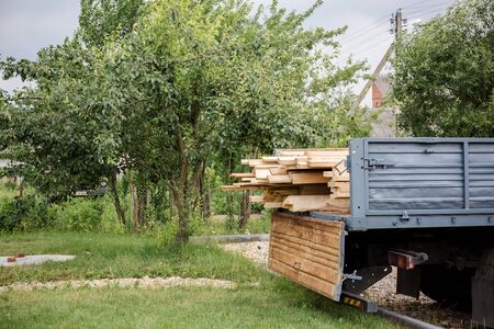 A planed board lies on board the truck. Building materials were brought to the construction site. Chopped wood for interior use. Cargo transportation of oversized items. With place for text.の写真素材