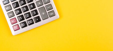 Large silver calculator with gray and black buttons on a yellow background. Conceptual photo of calculations, accounting, computing, profit, loss, tax with place for text.の写真素材