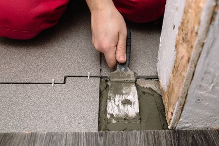 A man puts cement with a spatula for laying tiles. Finishing is one of the stages of repairing an apartment. Close-up of hands in the process.の写真素材