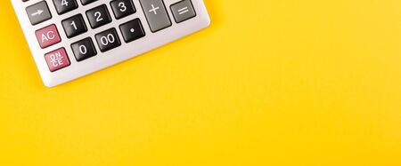 Large silver calculator with gray and black buttons on a yellow background. Conceptual photo of calculations, accounting, computing, profit, loss, tax with place for text.の写真素材