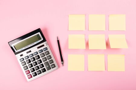 Banner with calculator, black pen and clean stickers on a pink background with place for text. Business concept. Tear-off paper for notes, reminders or quick messages, organazer of thoughts and ideas.の写真素材