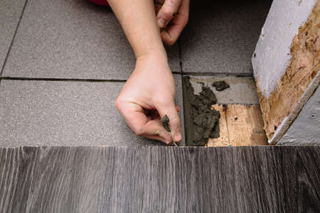 A man puts cement with a spatula for laying tiles. Finishing is one of the stages of repairing an...