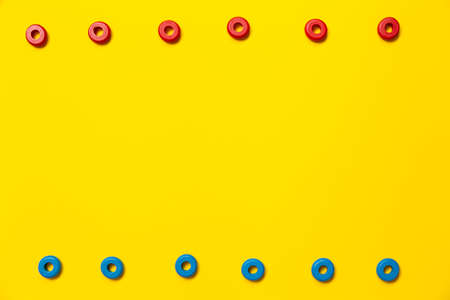 On a yellow background, there are rings of red and blue colors of the same size, which form a frame on children's education and development. Backdrop for placing text and other information.の写真素材