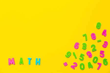The word math is written on a yellow background in colored plastic toy letters. Nearby are numbers...