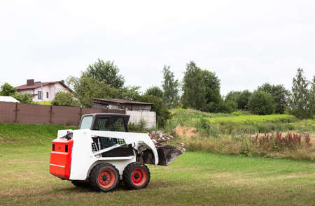 A skid steer loader clears the site for construction. Land work by the territory improvement....