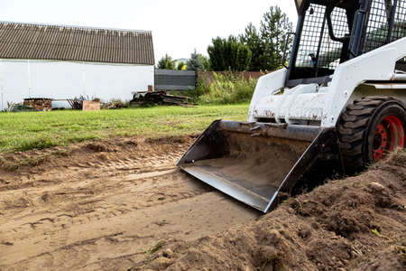 A skid steer loader clears the site for construction. Land work by the territory improvement....