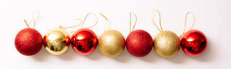 Christmas tree toys isolated on a white background. New year glitter balls red and gold color lie in an even rhythmic row. Long festive banner in fashion style. Close-up.の写真素材