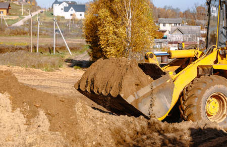 large yellow wheel loader aligns a piece of land for a new building. Preparation of the land for the...
