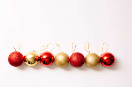 Christmas tree toys isolated on a white background. New year glitter balls red and gold color lie in an even rhythmic row. Festive banner with place for text in fashion style. Close-up.の写真素材