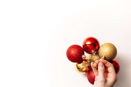 Christmas tree toys in hand isolated on a white background. Seven new year glitter balls of red and gold color. Festive banner with place for text in fashion style. Close-up.の写真素材
