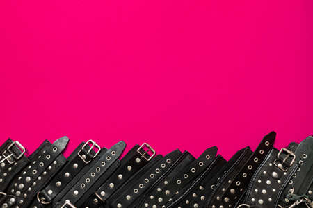 Pink color banner with black leather bracers and metal rivets for shackling hands or legs and performing sexual games. BDSM subject. Background for advertising adult products and sex toy store.の写真素材