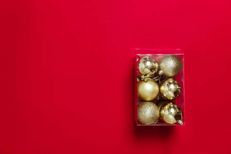 Golden Christmas balls-toys are packed in a transparent plastic box. Preparing for the Christmas holidays. Banner for a store selling Christmas decorations. Post-holiday cleaning.の写真素材