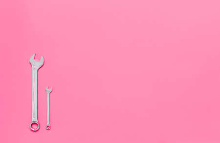 Two metal wrenches of different sizes isolated on pink background with copy space. Conceptual idea of the differences between: boss and employee, older and younger, big and small, parent and child.の写真素材