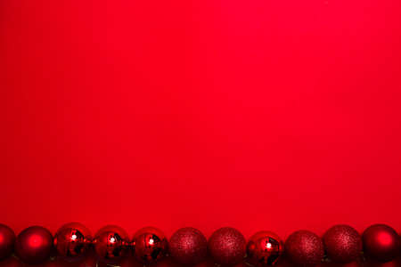 New Year banner with shiny Christmas balls on a red background. Postcard with a magical holiday atmosphere and a cheerful mood.の写真素材