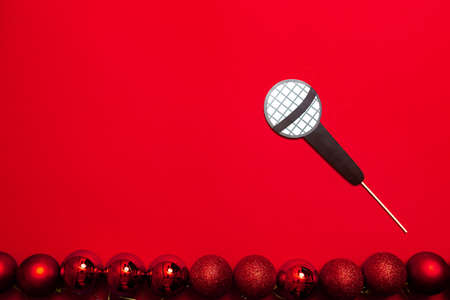A red color banner with microphone on a stick. A props for entertaining guests at a New Year corporate festive or a karaoke party. Public speaking, vocal lessons, or educational courses.の写真素材